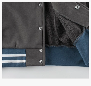 Close-up of children's baseball jacket showing warm black fleece lining and metal buttons