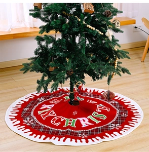 Detail of red Merry Christmas tree skirt with snowflake patterns and plaid ruffle edge