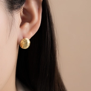 French style gold round pleated stud earrings with sunburst texture on a female model