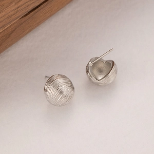 Detailed macro view of silver crinkled metal ball earrings with textured finish