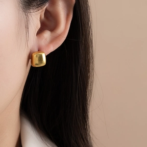 Boucles d'oreilles carrées minimalistes en or brossé portées pour un look moderne chic