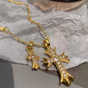 Macro shot of gold double cross pendants with sparkling zircons and fine chain detail