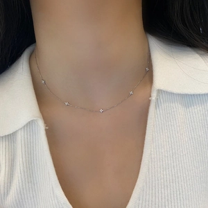 Close-up of delicate clover flower necklace with sparkling crystals on a woman's neck