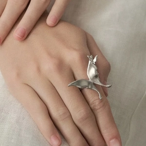 Minimalist silver butterfly wing ring with a matte metallic finish on a model's hand