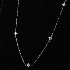 Macro detail of silver clover necklace with shimmering diamond accents on black velvet