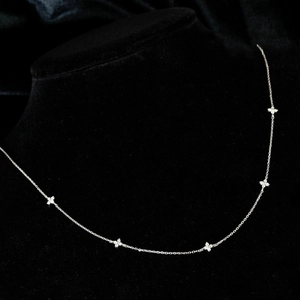 Macro shot of silver clover necklace with five small diamond-studded flower pendants
