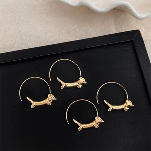 Élégantes boucles d'oreilles créoles teckel dorées sur un plateau à bijoux noir