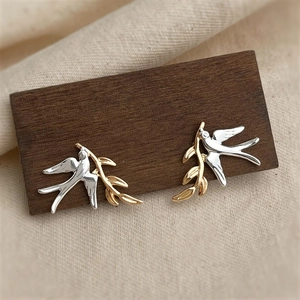 Elegant two-tone swallow bird stud earrings with golden branch in polished metal finish