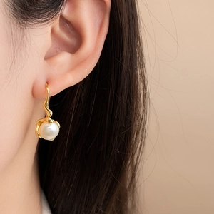 Elegant irregular natural pearl earrings with minimalist gold hooks worn by a model