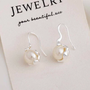 Detail view of irregular pearl earrings with elegant silver hooks on a jewelry card