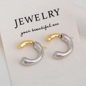 Macro detail of two-tone C-shaped hoop earrings in polished gold and silver metal finishes