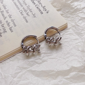 Detail of silver twisted spiral hoop earrings placed on a vintage book page backdrop