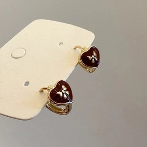 Detail of red heart earrings with golden bows on a white display card