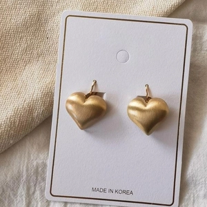 Brushed matte gold heart earrings on display card with warm knitted background
