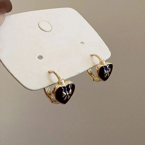 Elegant gold hoop earrings with black enamel heart charms and golden bow detail