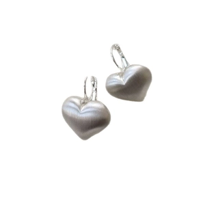 Macro detail of silver heart-shaped leverback earrings with a brushed metal finish texture