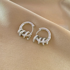 Silver hoop earrings with spiral twist texture on elegant champagne silk background