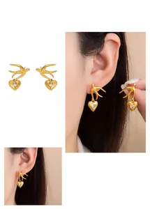 Macro detail of swallow zircon heart earrings in vintage gold plating for women