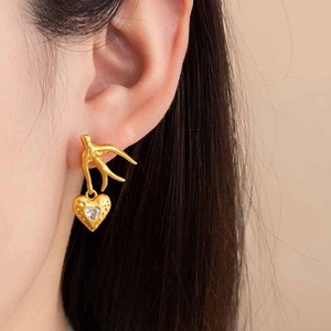 Golden swallow and heart earrings with zircon inlay worn on model for a premium look