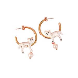 Détail de boucles d'oreilles dorées en C avec chat en émail blanc et perle ronde