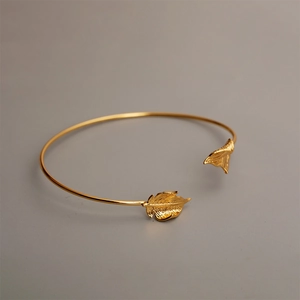 Detailed close-up of golden open cuff bracelet with intricate ginkgo leaf vein textures