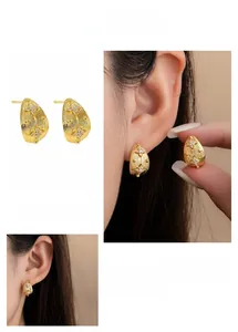 Detail of C-shaped gold metal stud earrings with vertical texture and zircon stars