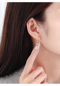 Detailed close-up of a silver Schnauzer dog safety pin earring worn by a model