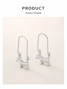 Detailed view of silver Schnauzer dog drop earrings on a vintage leather surface