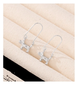 Macro shot of silver Schnauzer dog earrings on textured fabric showing fine craftsmanship