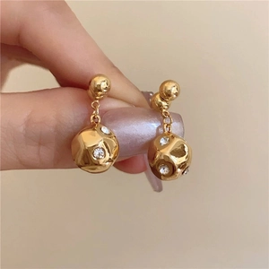 Chic gold-plated irregular ball earrings with white rhinestones held in hand