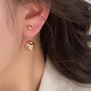 Minimalist gold ball drop earrings with zircons and hammered texture on female model