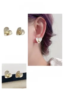 Détail de boucles d'oreilles cœur crème avec accent doré et finition texturée