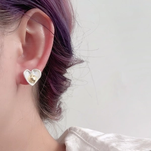 Élégantes boucles d'oreilles cœur double couche blanc et or portées par un mannequin