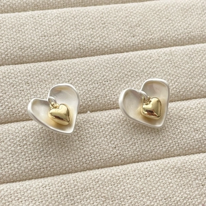 Détail de boucles d'oreilles cœur bicolores avec finition argent brossé et doré
