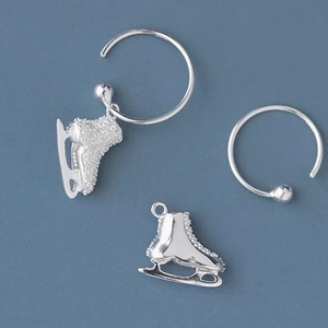 Detail of silver ice skate earrings with brushed and polished metal finishes