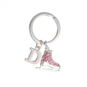 Close-up of a silver keychain with a letter D charm and a pink rhinestone ice skate pendant