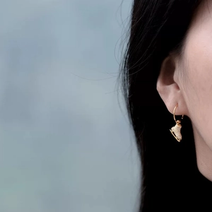 Sparkling gold ice skate earrings with pavé crystals worn on a model's ear