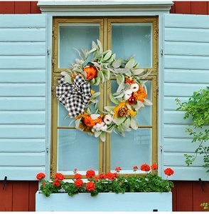 Macro view of fall wreath with white cotton balls and rustic plaid bow on a window