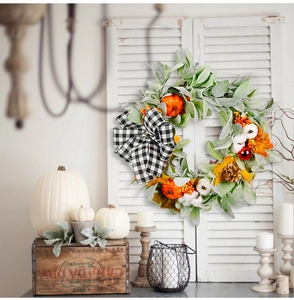 Autumn wreath with cotton, pumpkins and maple leaves hanging on a white wooden shutter