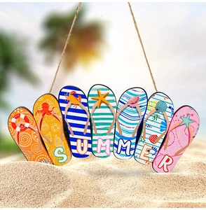 Close-up of wooden summer door sign with multi-color flip-flops and ocean icons in sand