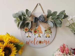 Detail of farmhouse welcome sign with sunflower gnomes and decorative greenery