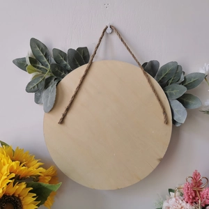 Close-up of blank round wooden sign with hanging rope and artificial lamb ear leaves