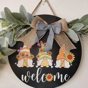 Detail of wooden welcome sign featuring three gnomes and sunflower decor with burlap bow