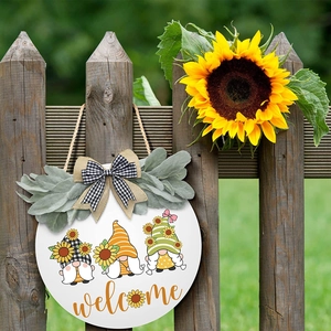 Detail of farmhouse welcome sign with three gnomes and sunflower on dark wooden fence