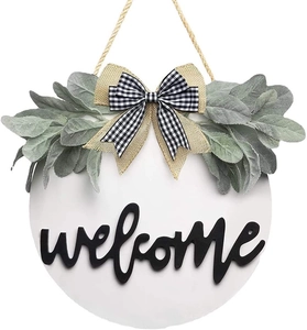 Detail of the rustic wooden welcome sign featuring a burlap bow and green leaves