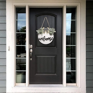 Detailed view of the welcome sign with a black and white bow and greenery on a black door
