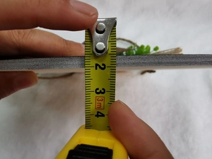 Κοντινή λήψη που μετρά το πάχος 5-6 mm της ξύλινης πινακίδας με μια μετροταινία