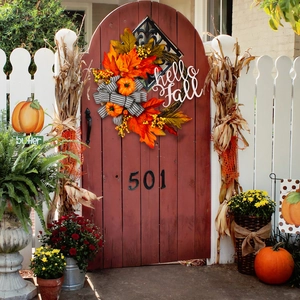 Detail of autumn wreath with pumpkins and hello fall sign hanging on a rustic wooden door