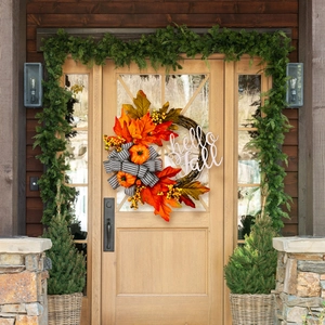 Detail of hello fall sign on autumn wreath with pumpkins, maple leaves and striped bow