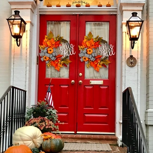 Autumn wreath with hello Fall sign orange pumpkins and bow on red front door decoration